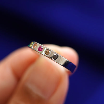 A solid yellow gold Rainbow Band turned to the side to show the black diamond, champagne diamond, ruby, and orange sapphire