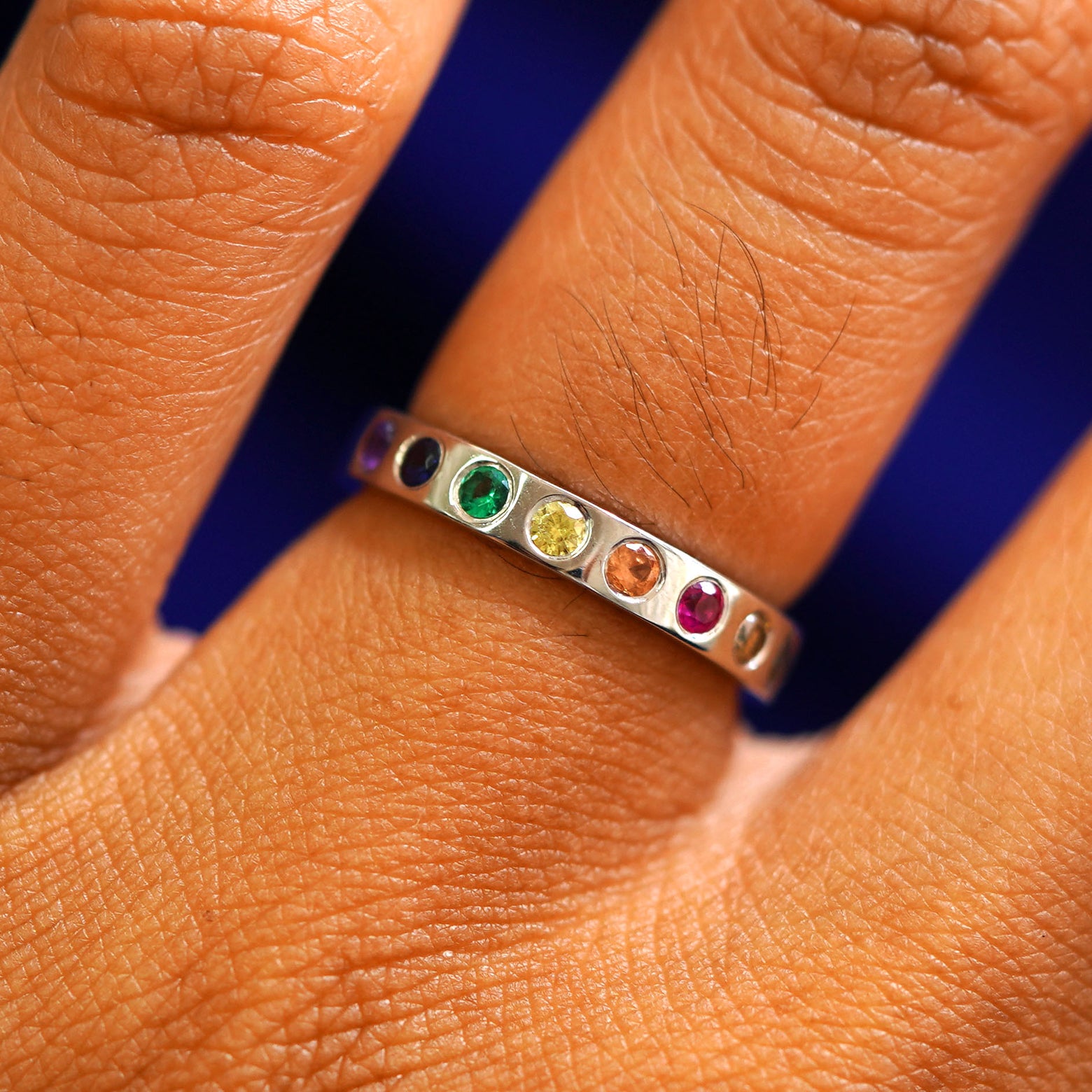 A 14k solid gold ring with an emerald, ruby, champagne and black diamonds, and sapphires of multiple colors in rainbow order