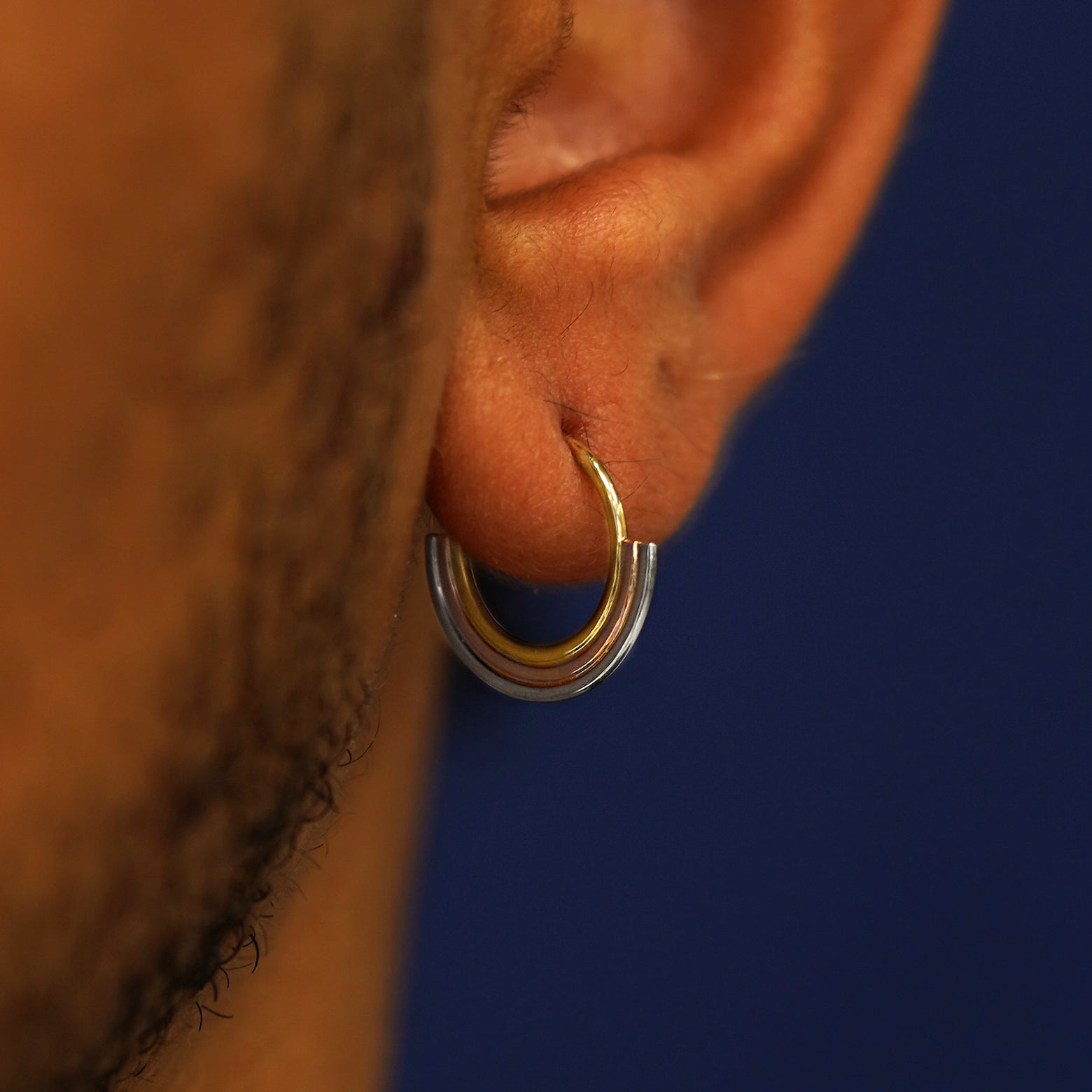 Close up view of a model's ear wearing a Rainbow Septum as a hoop earring