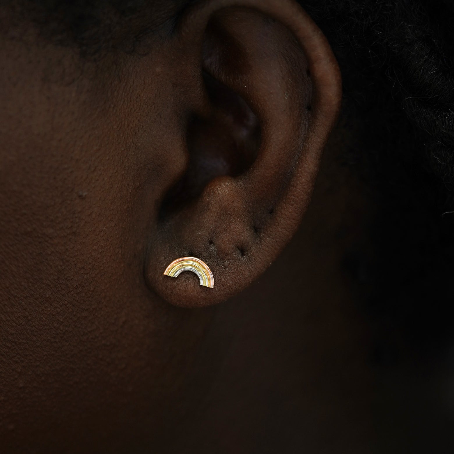 A model's ear wearing a tricolor 14k gold Rainbow Earring