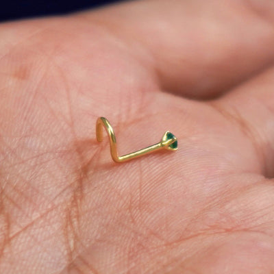 A model's palm holding a Emerald Gemstone Nose Stud to show the details of the screw