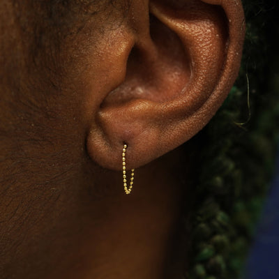 A model's wearing a 14k yellow gold Chain Loop Earring