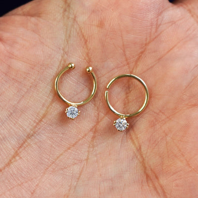 One Non-Pierced diamond and one Pierced diamond Septum ring both in 10mm resting in the palm of a model's hand