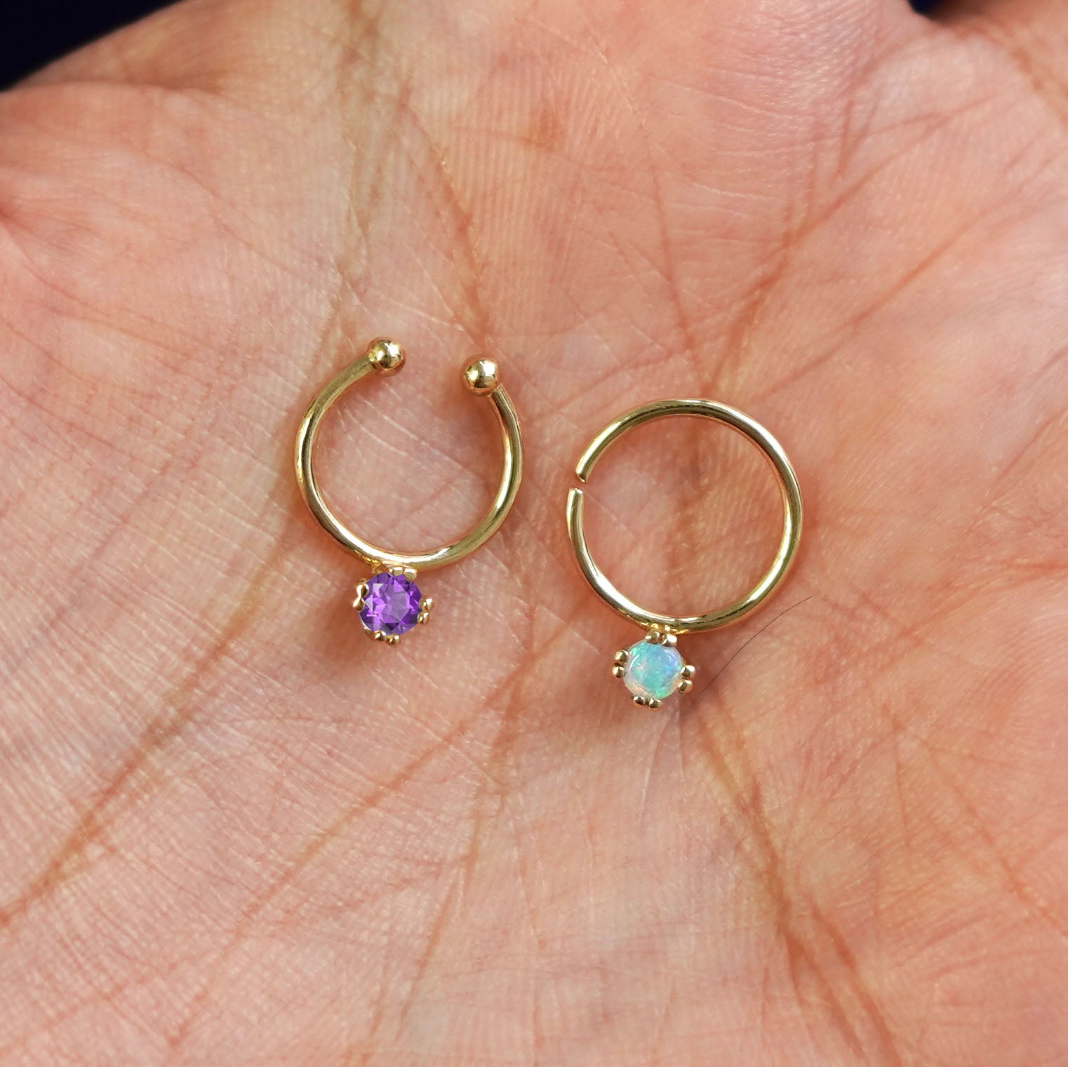 One Non-Pierced amethyst and one Pierced opal Gemstone Septum both in 10mm resting in the palm of a model's hand