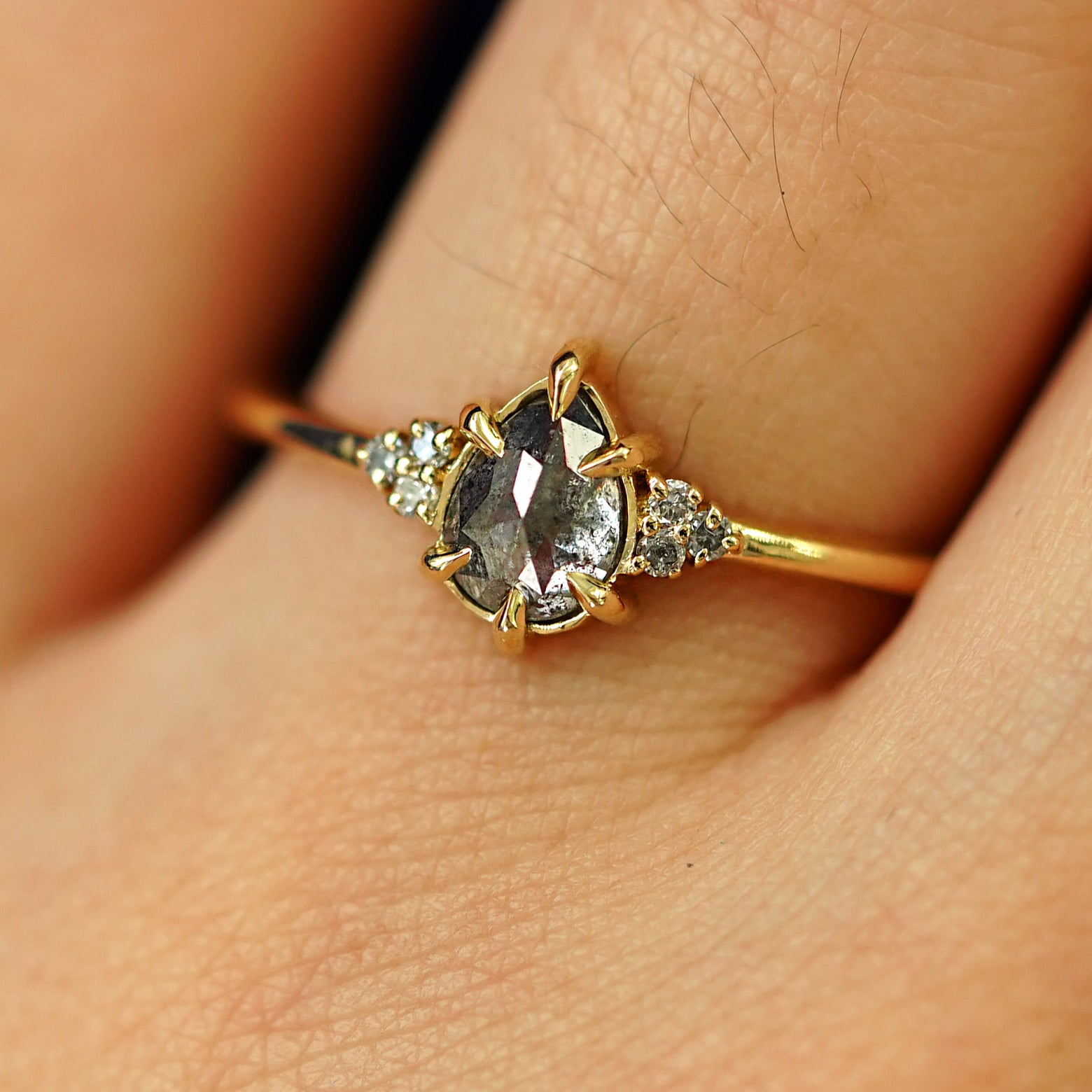 Close up view of a model's hand wearing a solid yellow gold Pear Salt and Pepper Diamond Ring