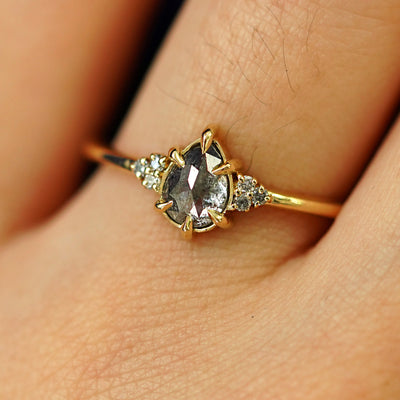 Close up view of a model's hand wearing a solid yellow gold Pear Salt and Pepper Diamond Ring