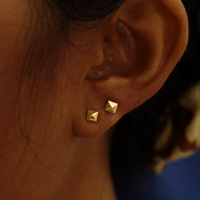 A model's ear wearing a pair of Pyramid stud earrings in two different lobe piercings on the same ear