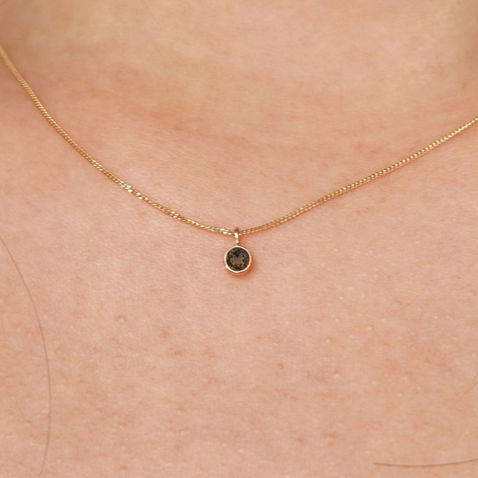 Close up view of a model's neck wearing a solid 14k yellow gold Smoky Quartz necklace