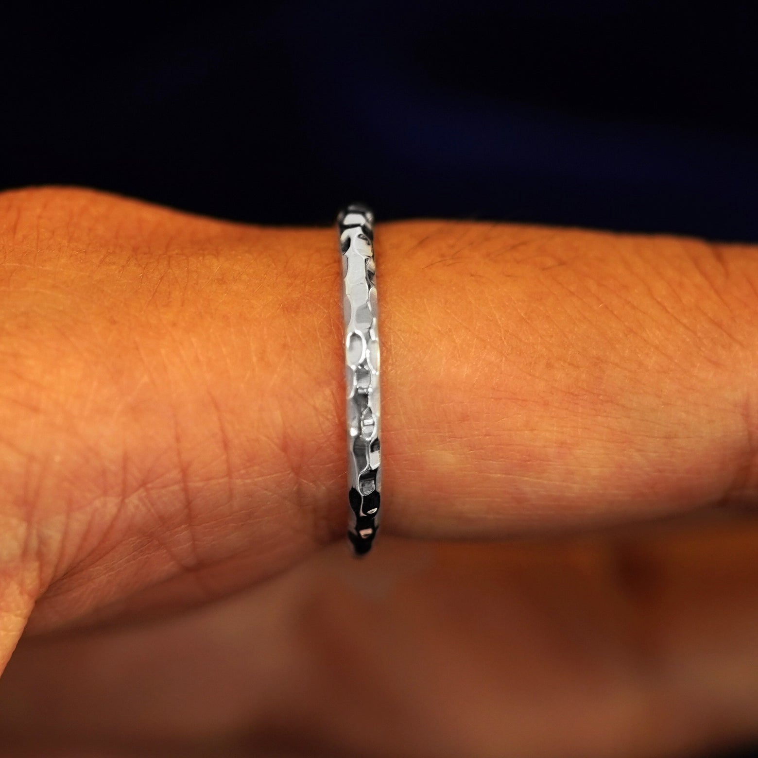 Side view of a Platinum Curvy Hammered Band on a model's finger
