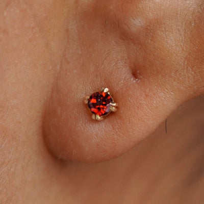 Close up view of a model's ear wearing a 14k yellow gold Garnet Earring