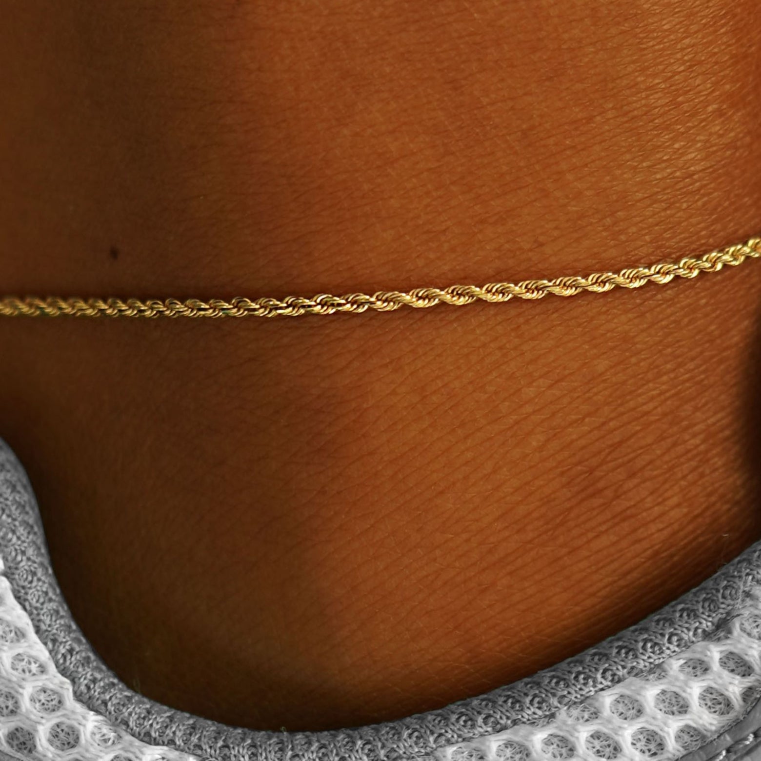 Close up view of a model's ankle wearing a yellow gold Rope Anklet