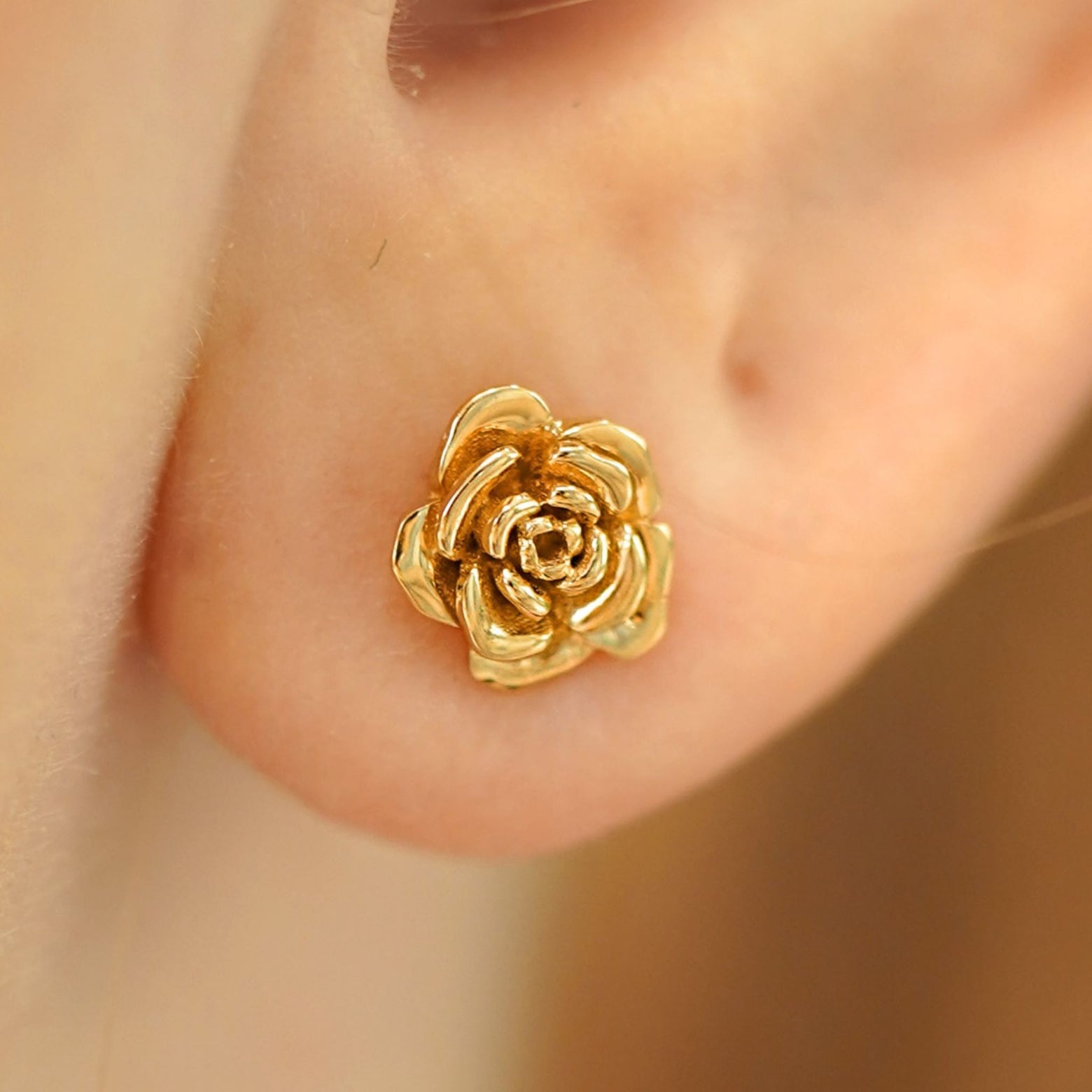Close up view of a model's ear wearing a 14k yellow gold Rose Earring