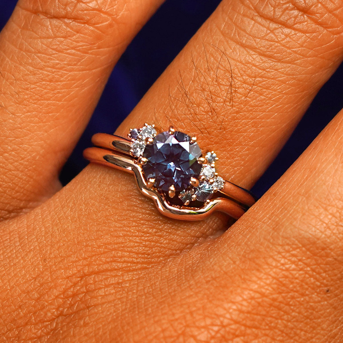 Close up view of a model's fingers wearing a 14k rose gold Alexandrite Cluster Ring Set