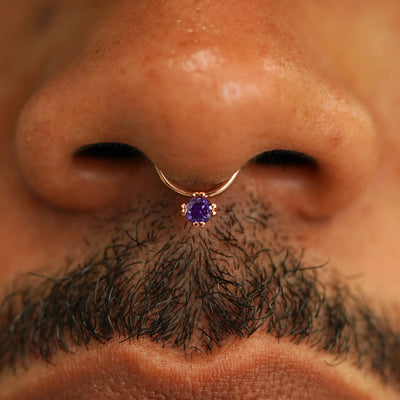 Close up view of a model's face wearing a 14k solid rose gold amethyst Gemstone Septum