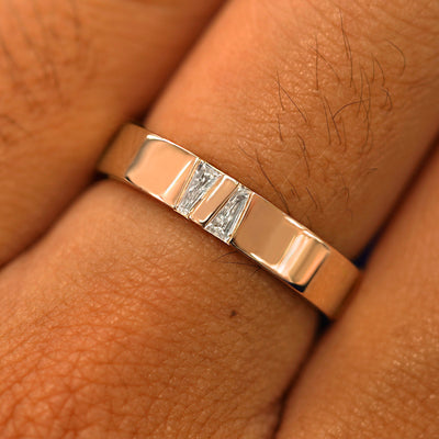 Close up view of a model's hand wearing a solid rose gold Double Baguette Diamond Band