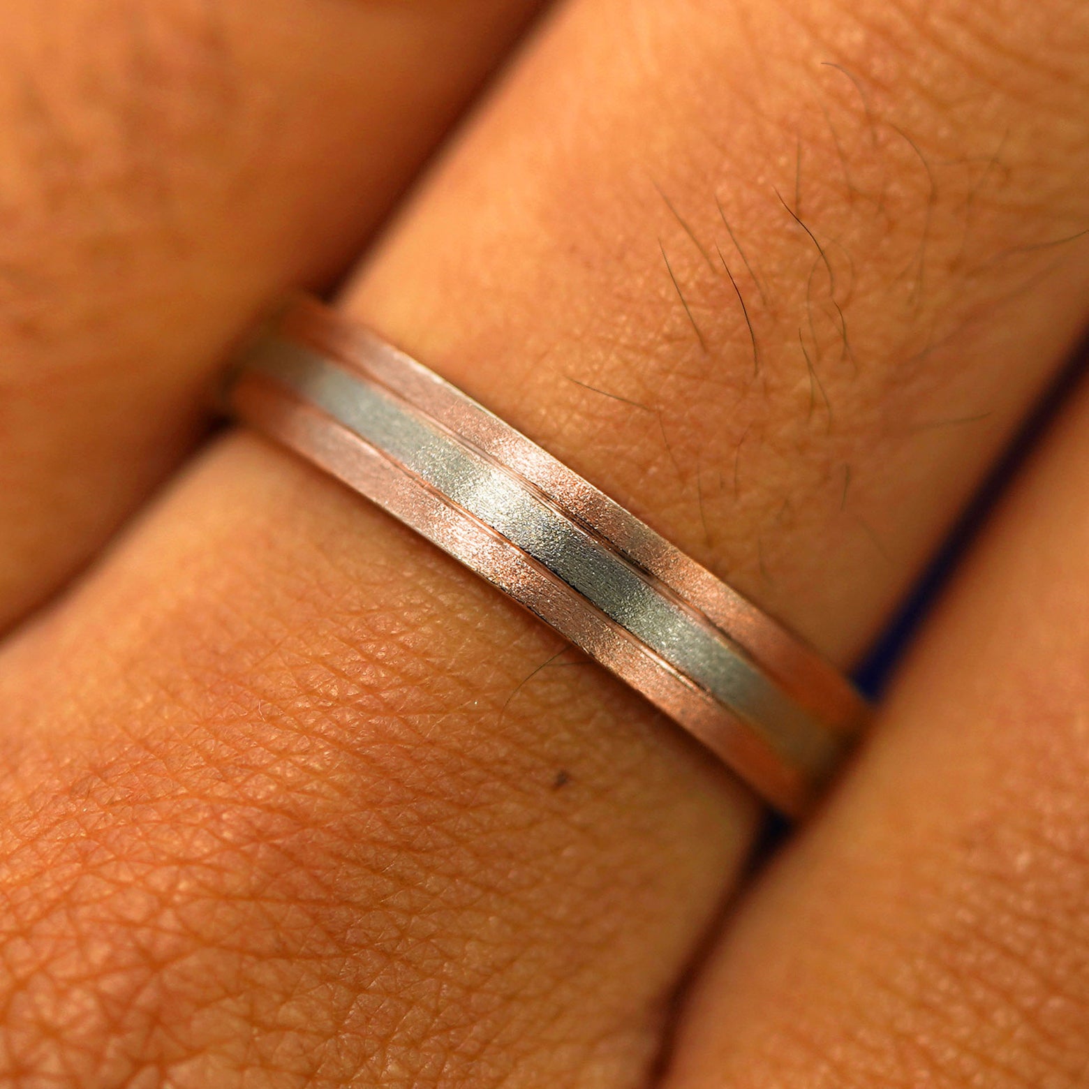 Close up view of a model's fingers wearing a 14k solid rose gold with champagne gold Inlay Band