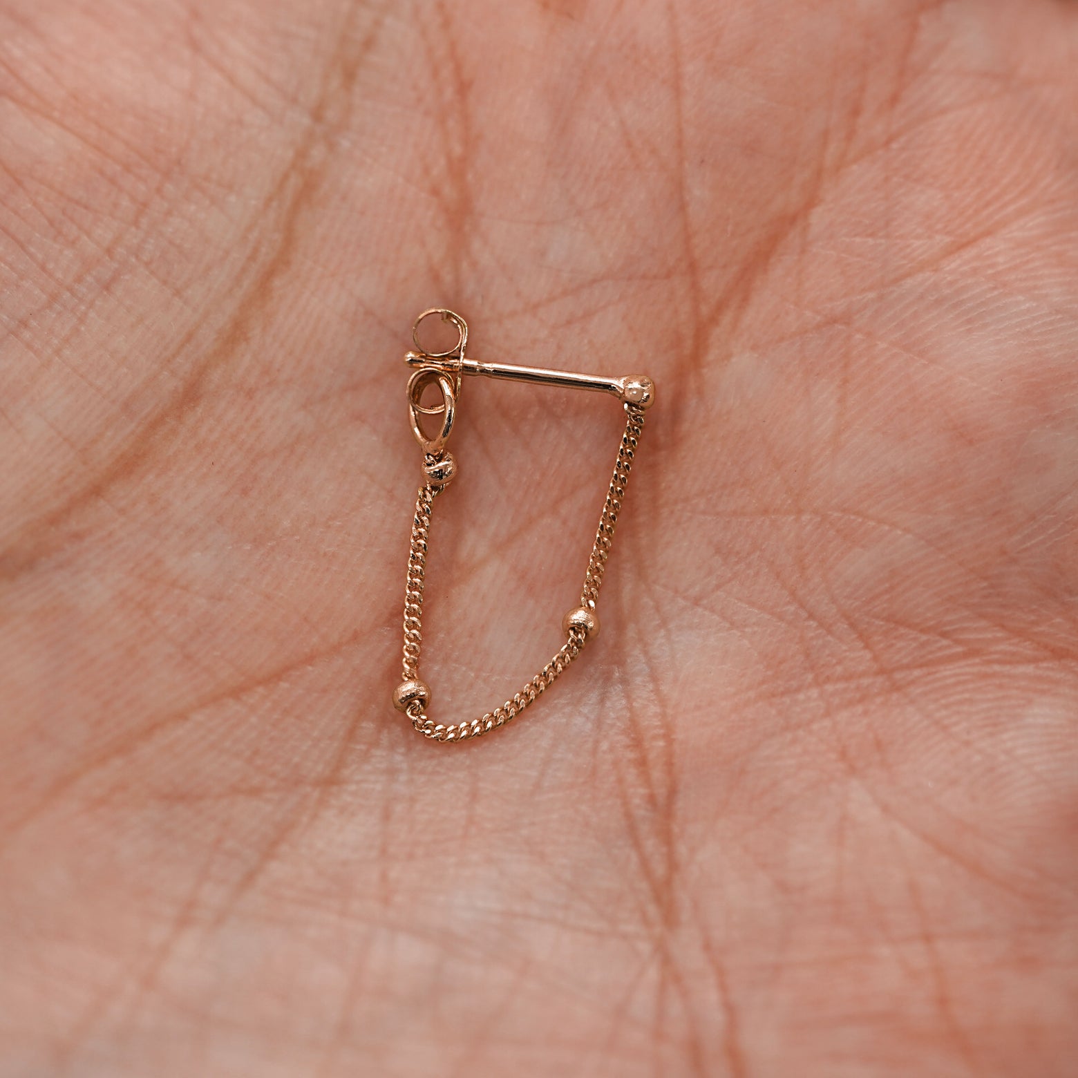 A rose gold Beaded Chain Loop Earring in model's palm