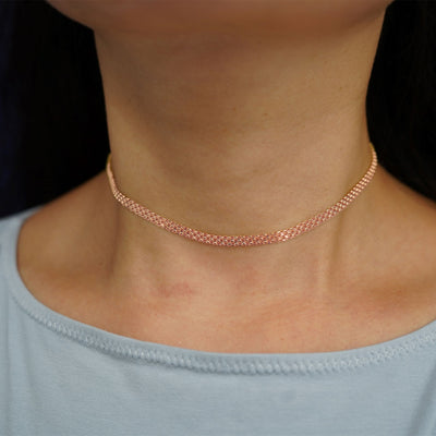 A model's neck wearing a solid 14k rose gold Bismarck Chain as a choker necklace