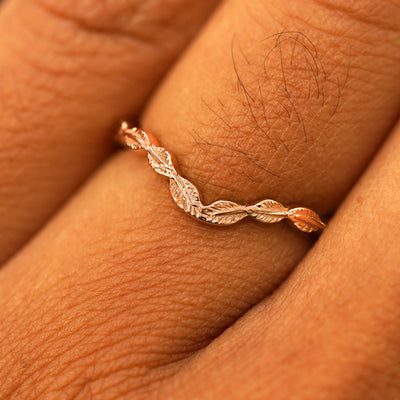 Close up view of a model's fingers wearing a 14k rose gold Chevron Leaves Band