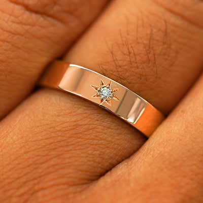 Close up view of a model's hand wearing a solid rose gold Engraved Star Diamond Band