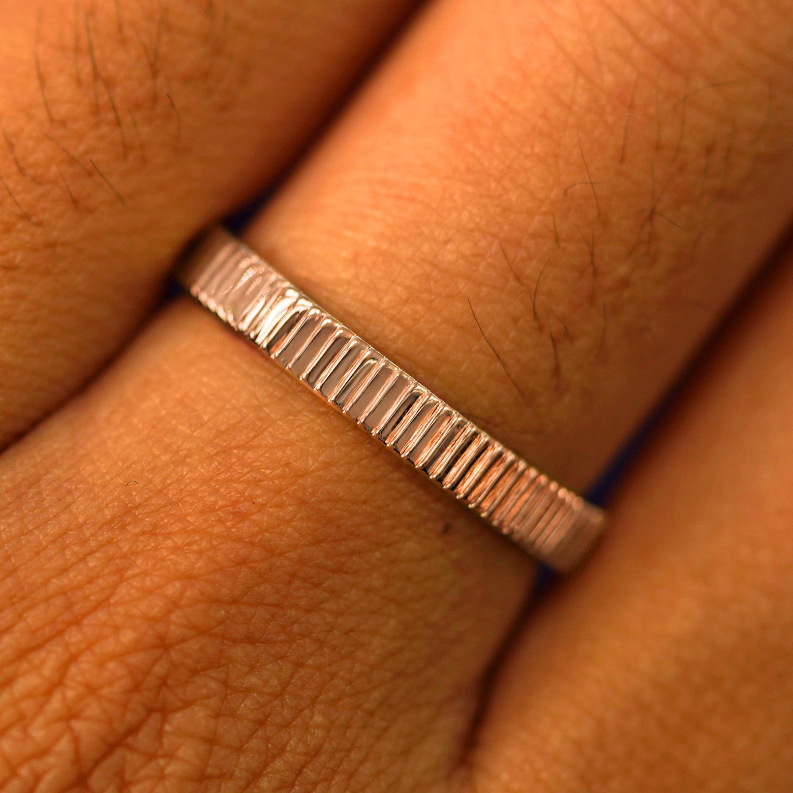 Close up view of a model's fingers wearing a 14k rose gold Edge Band