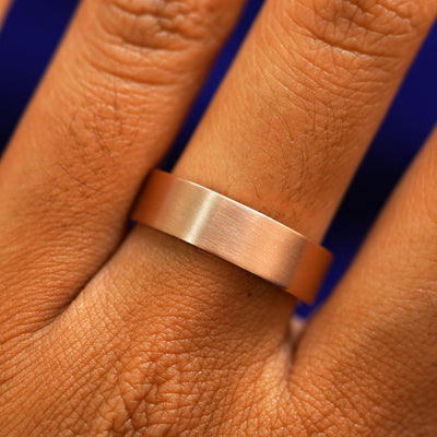 Close up view of a model's fingers wearing a 14k rose gold Industrial Matte Band