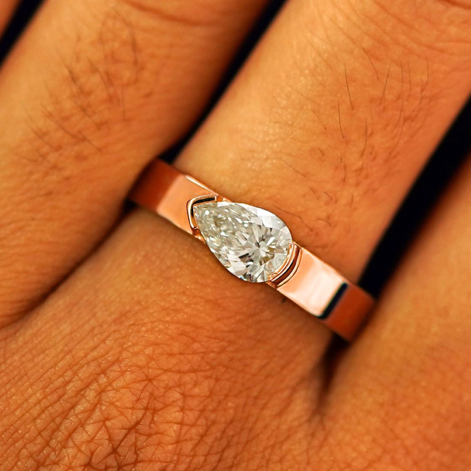 Close up view of a model's fingers wearing a 14k rose gold Lab Diamond Pear Ring