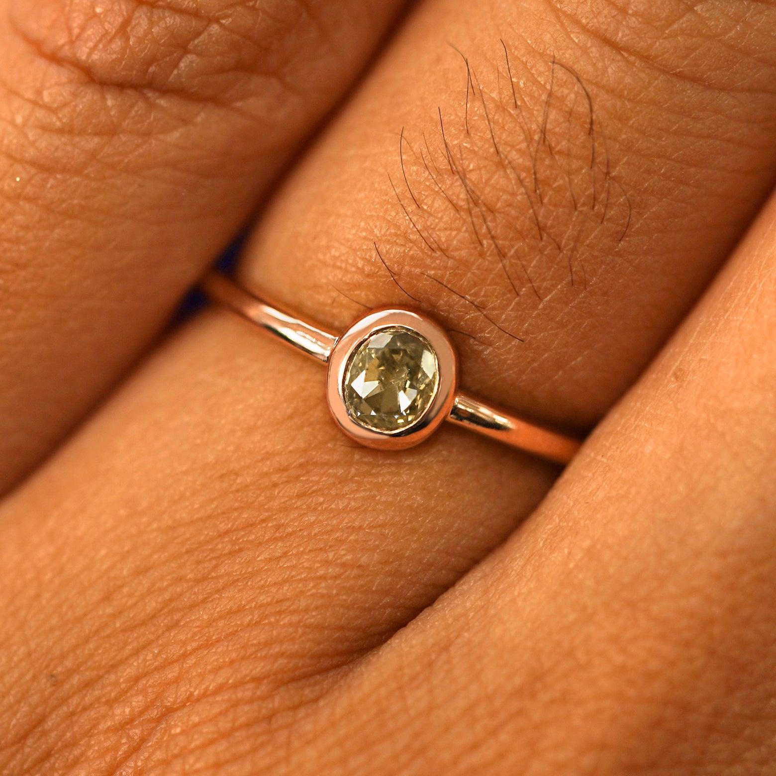 Close up view of a model's fingers wearing a 14k rose gold Oval Champagne Diamond Ring