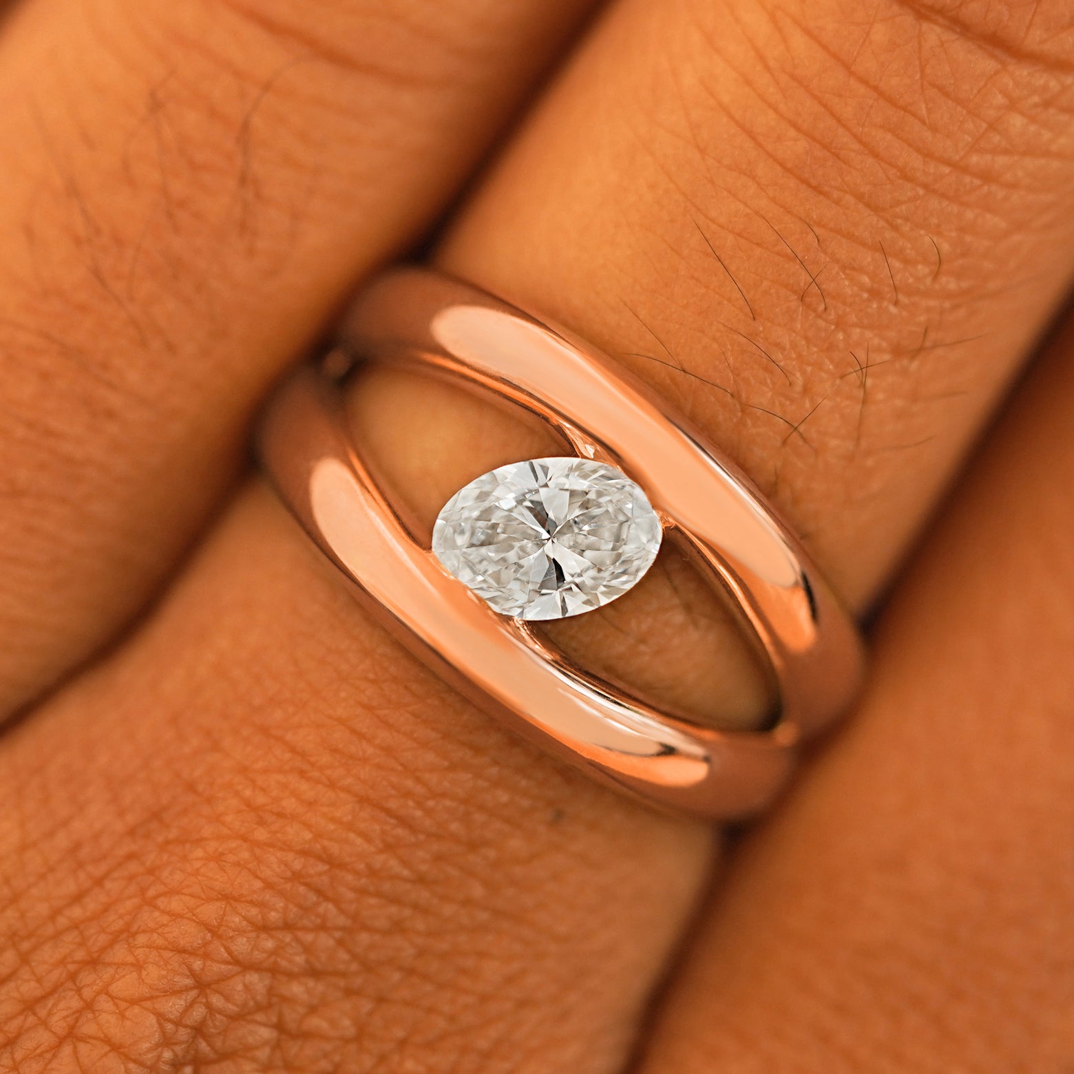 Close up view of a model's fingers wearing a 14k rose gold Oval Lab Diamond Tension Ring