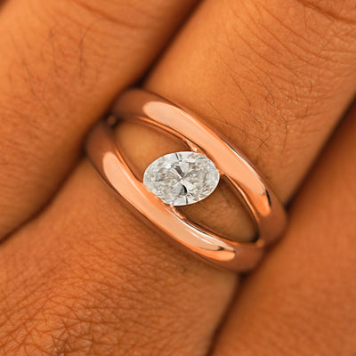 Close up view of a model's fingers wearing a 14k rose gold Oval Lab Diamond Tension Ring