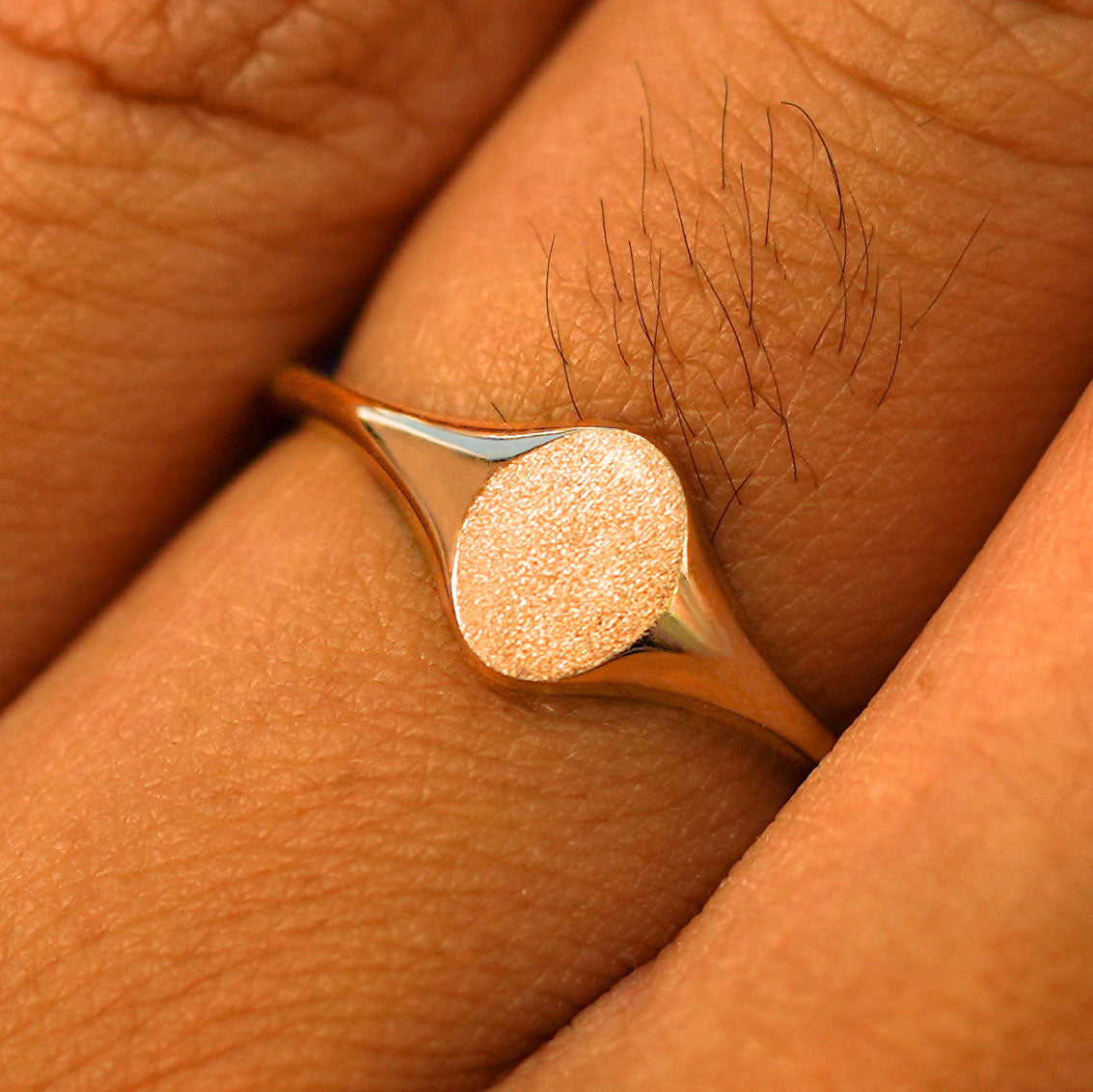 Close up view of a model's fingers wearing a 14k rose gold Oval Signet Ring