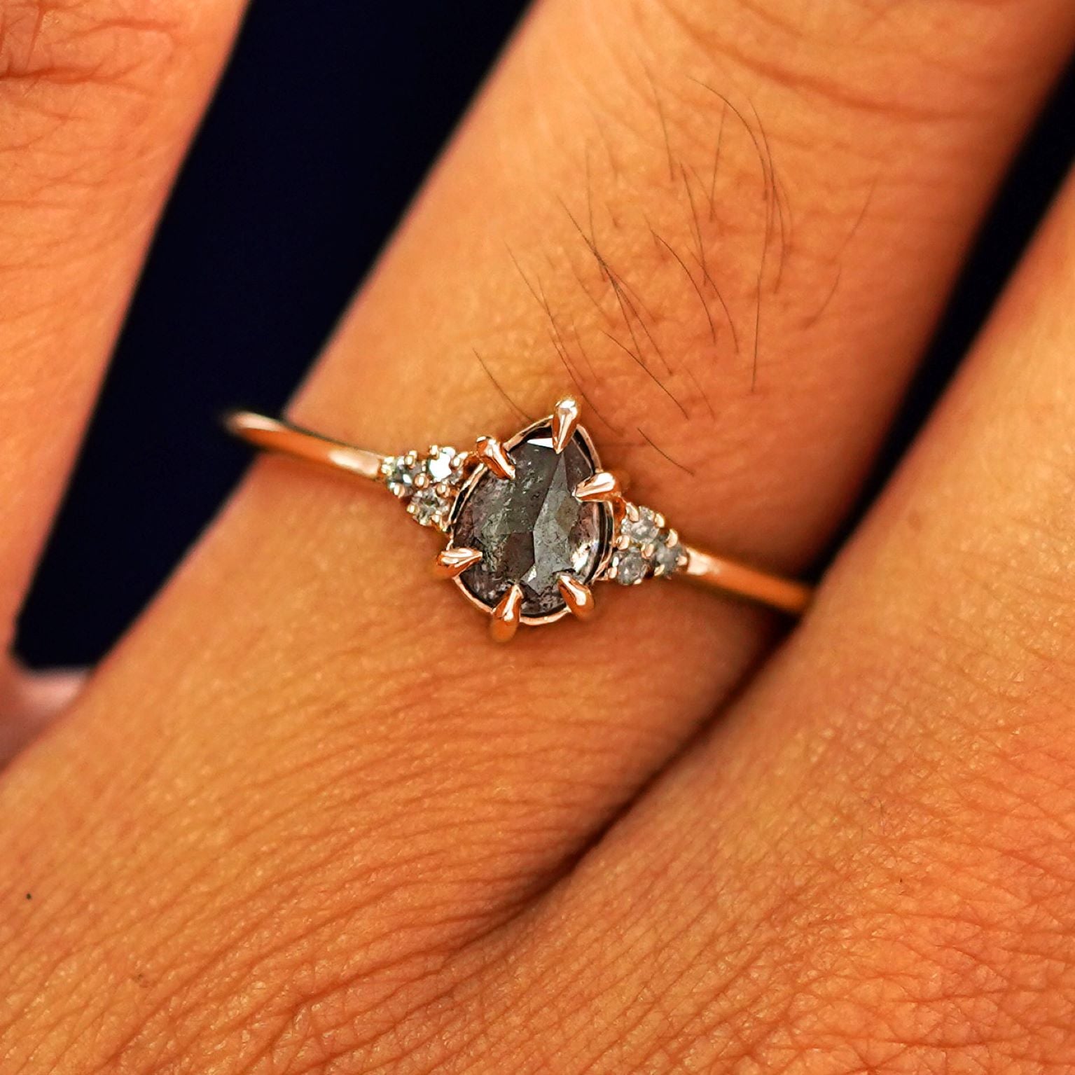 Close up view of a model's fingers wearing a 14k rose gold Pear Salt and Pepper Diamond Ring