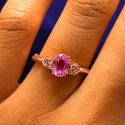 Close up view of a model's fingers wearing a 14k rose gold Pink Sapphire Roses Ring