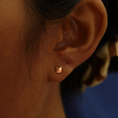 A model's ear wearing a 14k rose gold Pyramid Earring