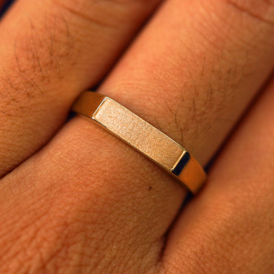 Close up view of a model's fingers wearing a 14k rose gold Rectangular Signet Ring