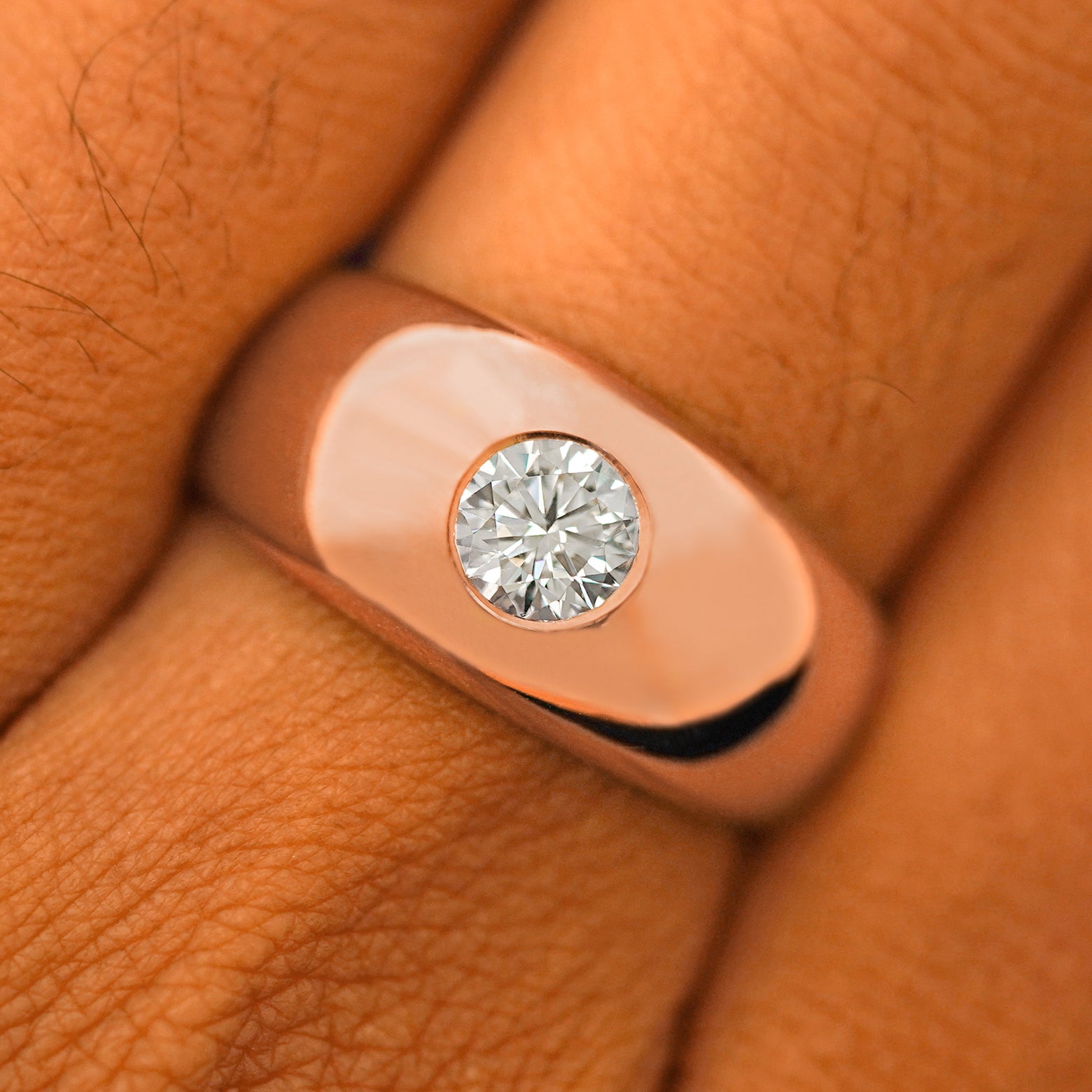 Close up view of a model's fingers wearing a 14k rose gold Round Lab Diamond Puffy Signet Ring