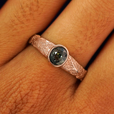 Close up view of a model's fingers wearing a 14k rose gold Dark Green Sapphire Pine Ring