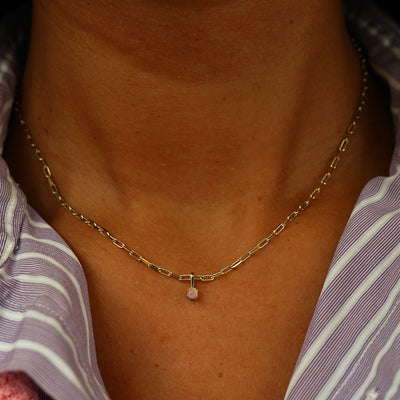 Close up view of a model's neck wearing a yellow gold Rose Quartz Charm on a Butch Chain