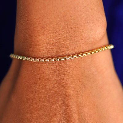 A model's wrist wearing a yellow gold Round Box Chain Bracelet