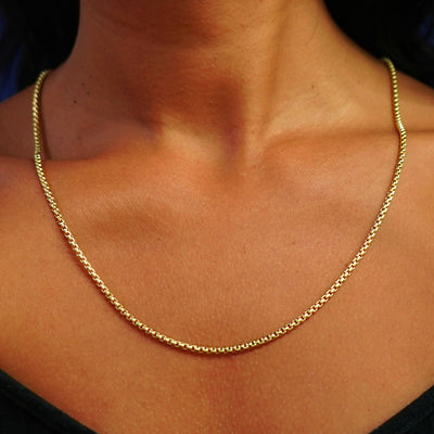 Close up view of a model's neck wearing a yellow gold Round Box Chain 