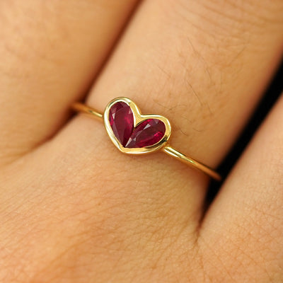 Close up view of a model's hand wearing a solid yellow gold Ruby Heart Ring