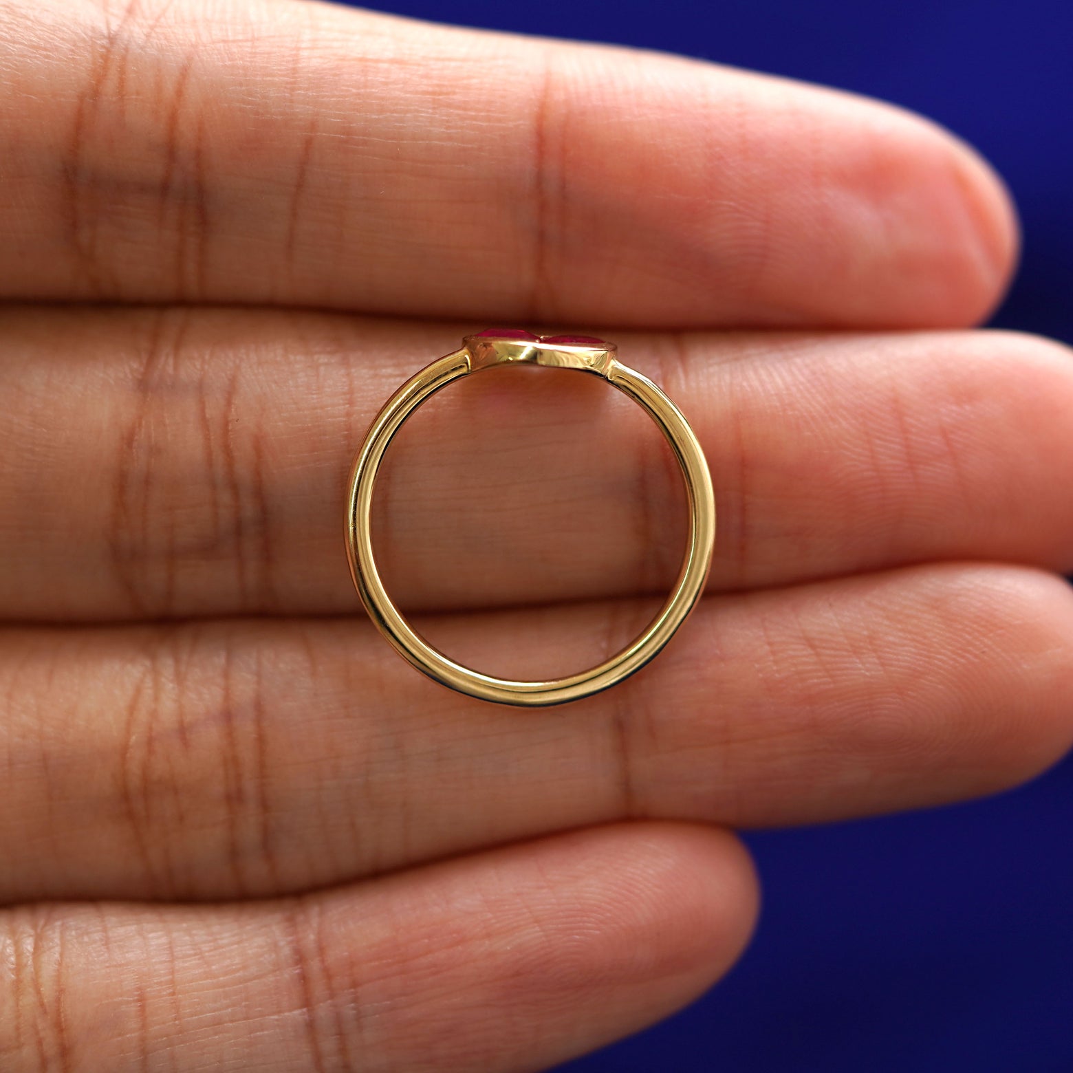 A yellow gold Ruby Heart Ring in a model's hand showing the thickness of the band