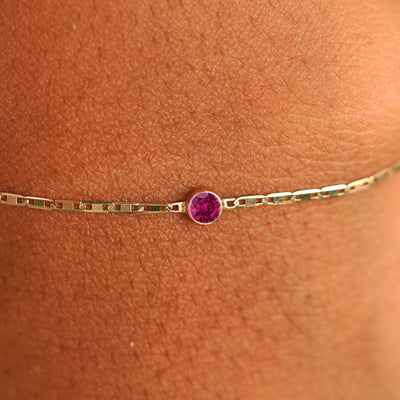 Close up view of a models wrist wearing 14k yellow gold Ruby Bracelet