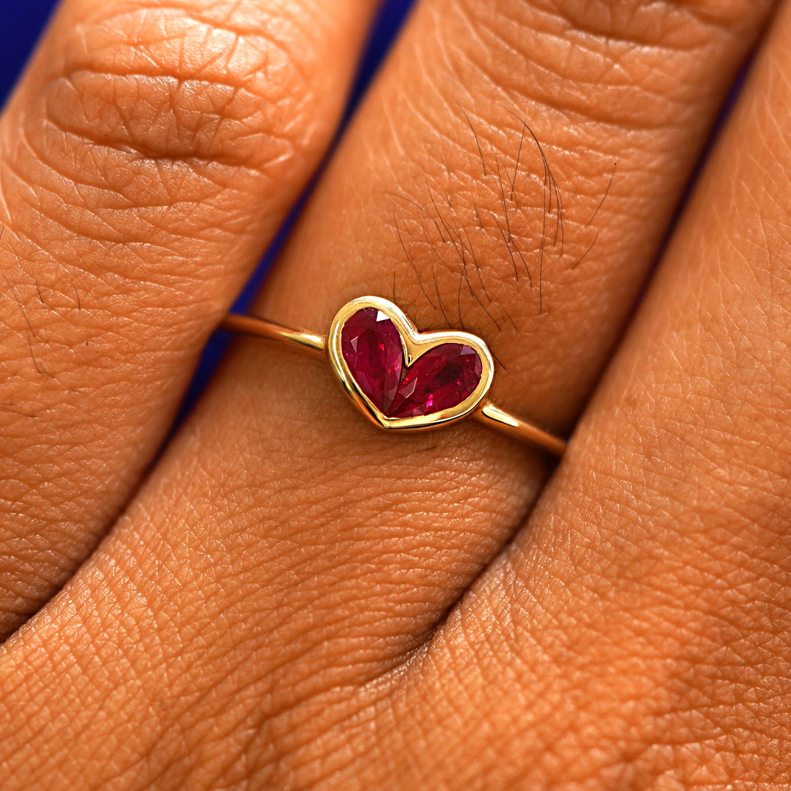 Close up view of a model's fingers wearing a 14k yellow gold Ruby Heart Ring