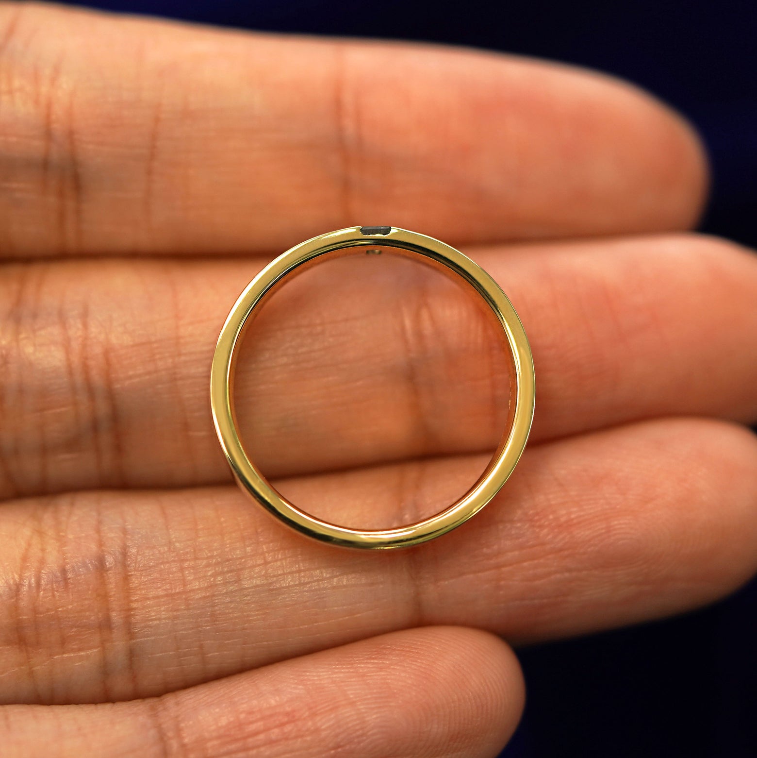 A yellow gold Salt and Pepper Baguette Diamond Band in a model's hand showing the thickness of the band