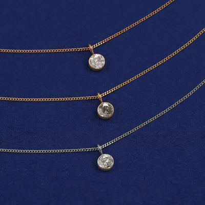 Three versions of the Salt and Pepper Diamond Necklace in options of yellow, white, and rose gold on a dark blue background