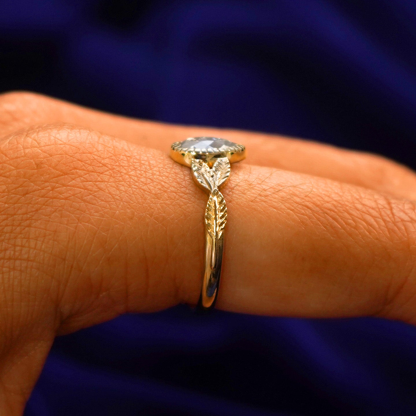 Side view of a Pear Salt and Pepper Diamond Leaves Ring on a model's finger