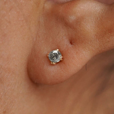 Close up view of a model's ear wearing a 14k yellow gold Salt and Pepper Diamond Earring