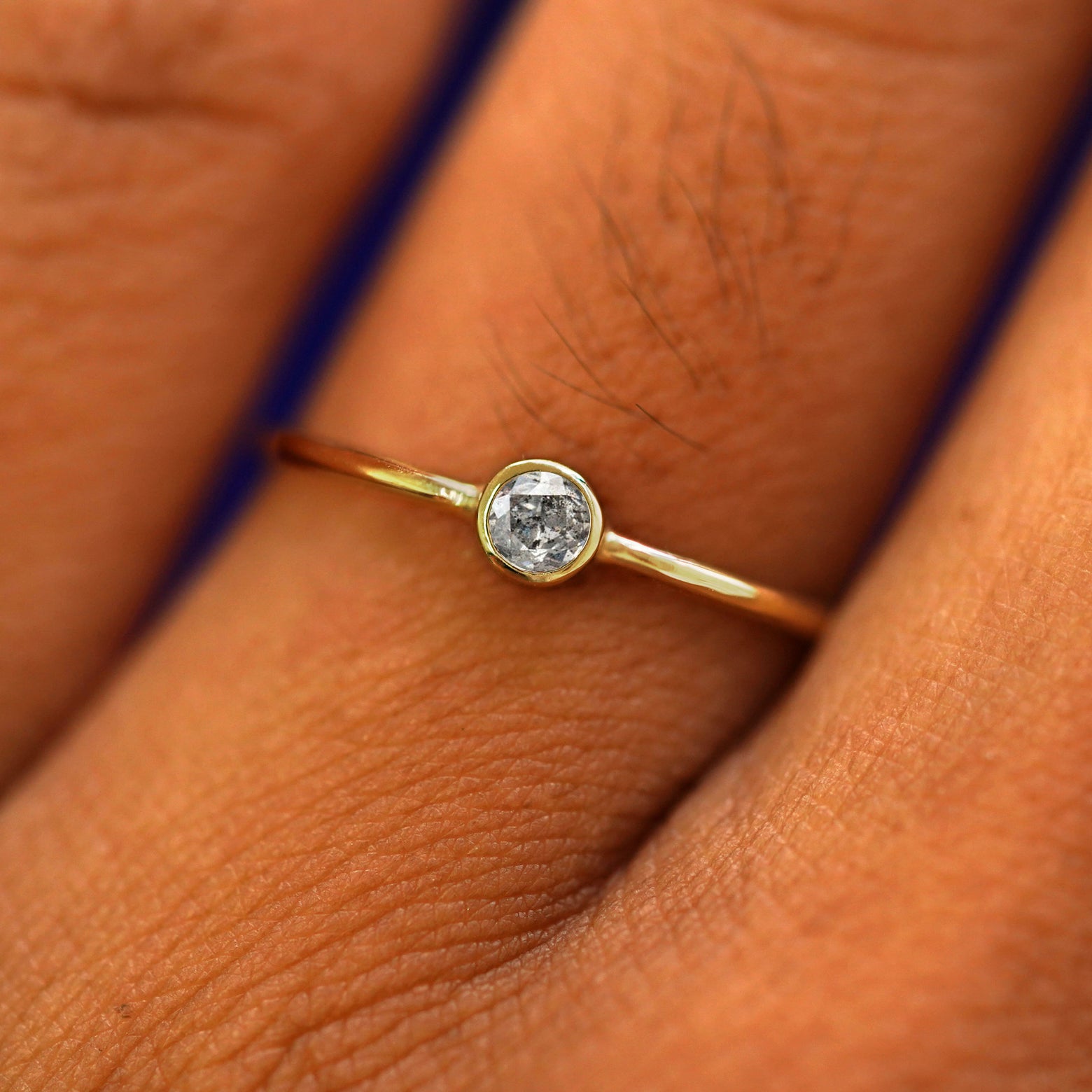 Close up view of a model's fingers wearing a 14k yellow gold Salt and Pepper Diamond Ring