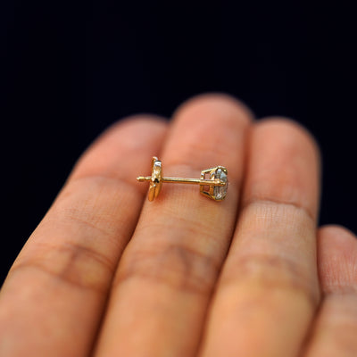 A 14k gold Salt and Pepper Diamond Pressure Lock Earring resting sideways on a model's fingertips to show detail